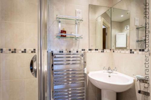 W łazience znajduje się umywalka, toaleta i lustro. w obiekcie Headford Cottage w mieście Stow on the Wold