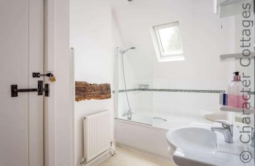 a white bathroom with a shower and a sink at April Cottage in Mickleton