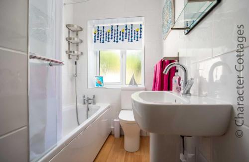 a bathroom with a sink and a tub and a toilet at Tukes Cottage in Chipping Norton