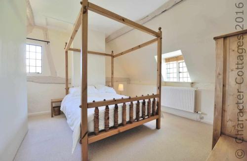 a bedroom with a wooden canopy bed in a room at Pye Corner Cottage in Broadway