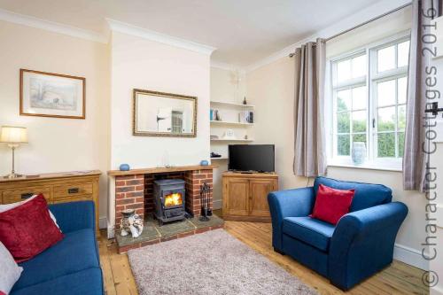 a living room with two blue chairs and a fireplace at Swan View in Southrop