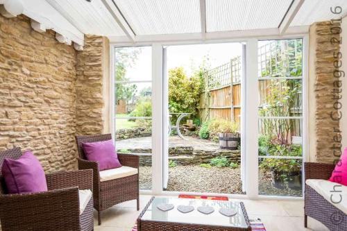 a living room with purple cushioned chairs and a glass door at Swan View in Southrop
