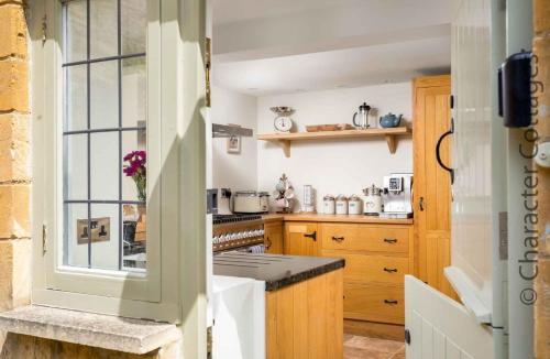 a kitchen with wooden cabinets and a window at Wyncliffe in Chipping Campden