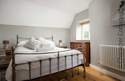 um quarto com uma cama com lençóis brancos e um radiador em Wyncliffe em Chipping Campden