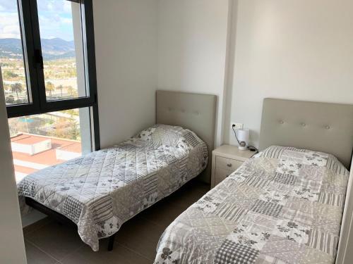 two beds in a room with a window at Apartamento Infinium I - Exclusivo - Inmodream Calpe in Ifach