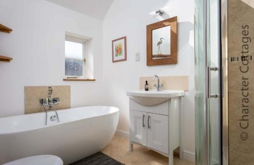 a white bathroom with a tub and a sink at High Ridge in Idbury