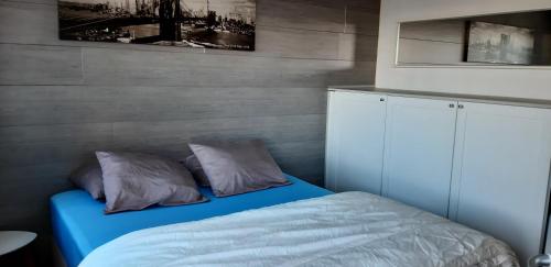 a bedroom with a blue bed with two pillows at Residentie Spinnaker in Blankenberge