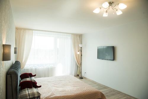 a white bedroom with a bed and a window at Cozy 3 bedroom apartament in town centre of Joniškis in Joniškis