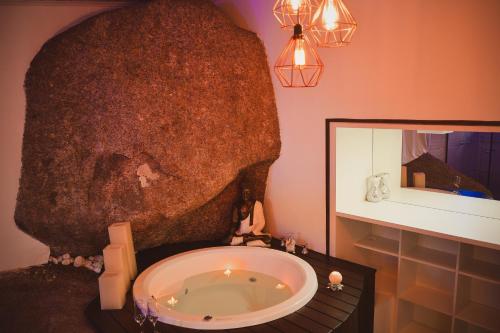 a bathroom with a large rock next to a bath tub at Pousada Hostel Albergue Explorer in Praia do Rosa