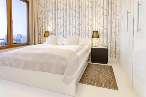 a white bedroom with a large bed and a wall at VacationClub - Olympic Park Apartament A602 in Kołobrzeg