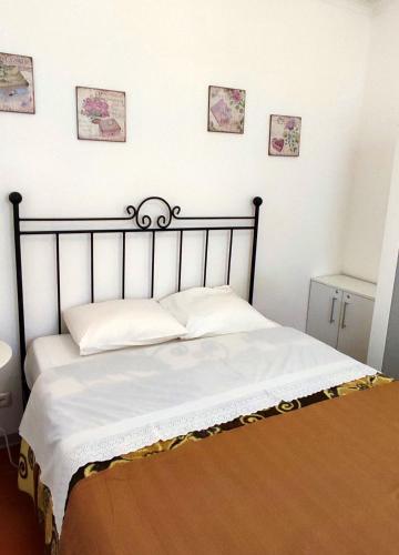 a bed in a bedroom with four pictures on the wall at Casinha alentejana in Évora