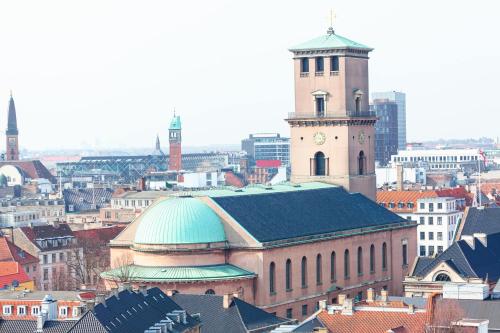a large building with a clock tower in a city at City Apartment With Exposed Ceiling Beams in Copenhagen