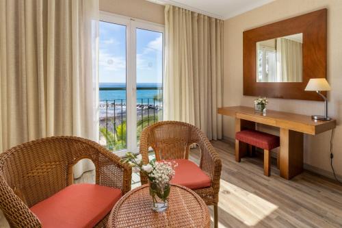 a hotel room with a table and chairs and a desk at Enotel Sunset Bay in Ponta do Sol