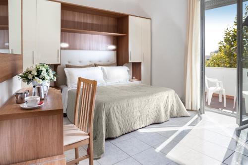 a bedroom with a bed and a table with a chair at Hotel Stacchini in Cesenatico