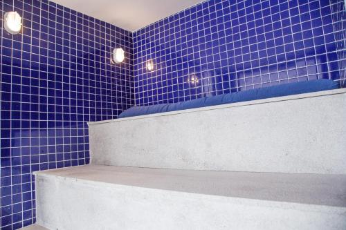 a blue tiled bathroom with a bench and lights at ATH Hotel - Américas Townhouse in Rio de Janeiro
