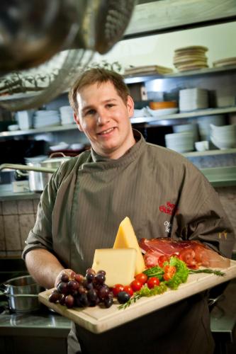 a man holding a tray of cheese and vegetables at Hotel Glöckner und Hotel Residenz Glöckner in Ischgl