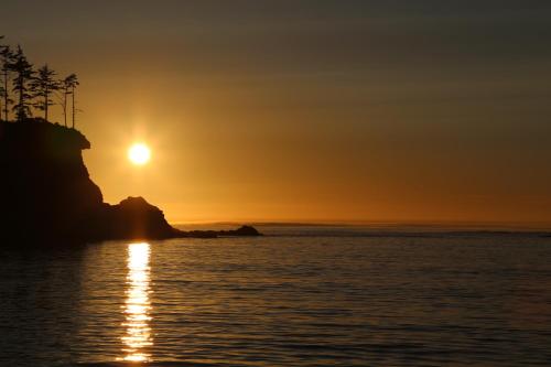 a sunset over the ocean with a rock in the foreground at Captain John's Motel in Charleston