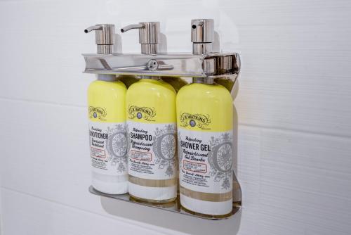 a rack with three bottles of disinfectants on a wall at Holiday Inn Express & Suites West Long Branch - Eatontown by IHG in West Long Branch