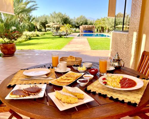 een houten tafel met ontbijtproducten en drankjes erop bij Marrakech Retreat By La Siredrah in Marrakesh