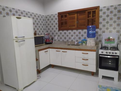 a kitchen with white cabinets and a white refrigerator at Casa com piscina - Prado in Prado