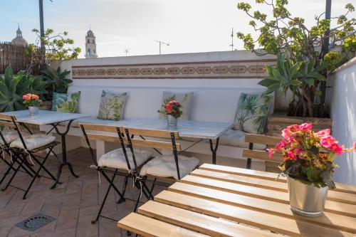 a table with chairs and a table with flowers on it at La Gitanilla Alojamiento con Encanto in Jerez de la Frontera