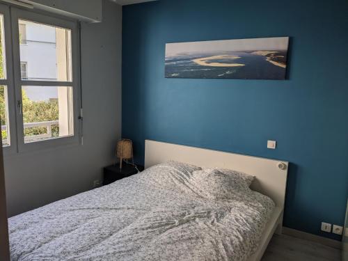 une chambre avec un lit avec un mur bleu dans l'établissement T3 à Mérignac, cosy et bien décoré, à Mérignac