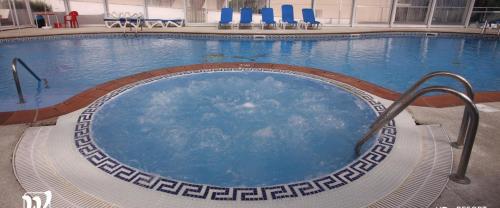 una gran piscina con sillas azules en un edificio en Apartamentos Las Sirenas, en Viveiro