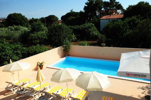 a swimming pool with chairs and umbrellas on a building at Apartments Klelija in Zadar