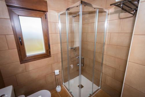 a bathroom with a shower with a toilet and a window at Apartamentos rurales El Torneru in Piloña