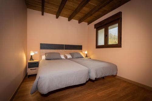 a bedroom with a large white bed and a window at Apartamentos rurales El Torneru in Piloña
