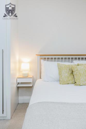 a bedroom with a white bed and a lamp on a side table at Castle Properties:Eton-The College in Windsor