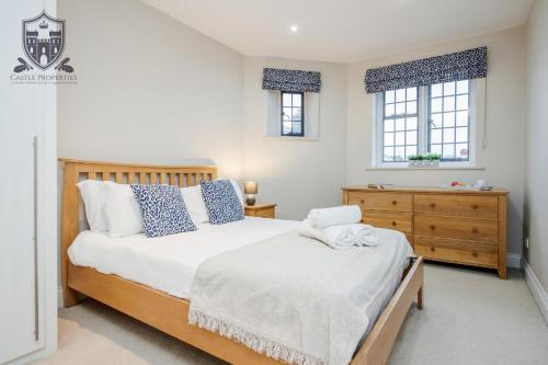a bedroom with a bed and a dresser and two windows at Castle Properties:Eton-The College in Windsor