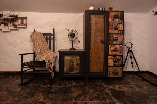 a room with a chair and a fan next to a wall at Resort Valea Tătarilor in Lacu Rosu