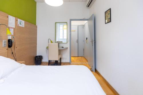 a bedroom with a bed and a desk and a table at Hôtel Edmond Rostand in Marseille