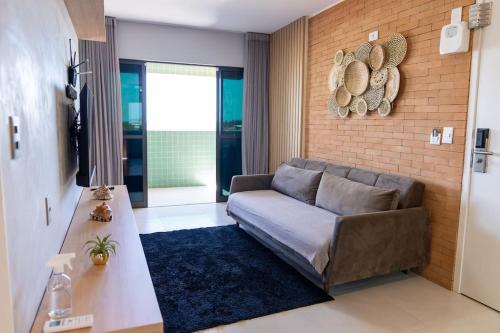 a living room with a couch and a brick wall at Apto 2 suites com elevador no Frances -Adm Nutelss in Praia do Frances