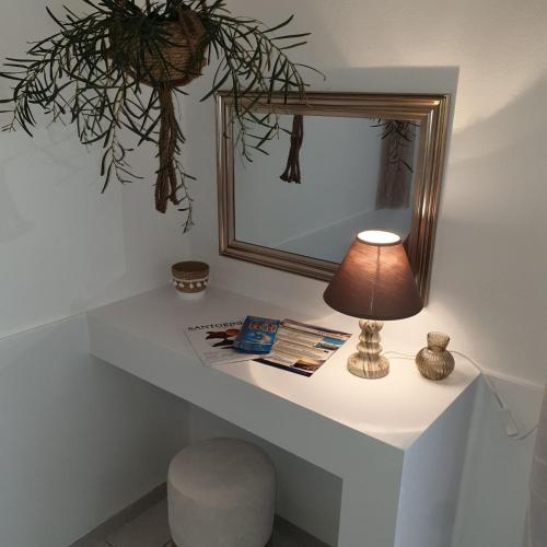 a table with a lamp and a mirror on it at Sagma Central Rooms in Perissa