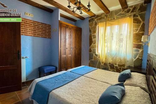 a bedroom with a bed with blue walls and a window at Casa el Mirador de Gredos Norte in Hoyocasero