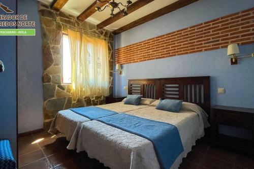 a bedroom with a large bed with blue sheets at Casa el Mirador de Gredos Norte in Hoyocasero
