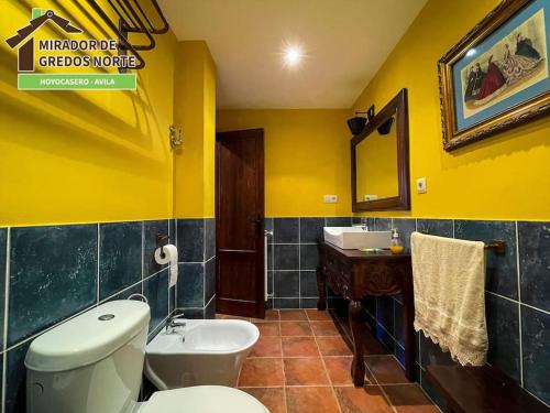 a yellow bathroom with a toilet and a sink at Casa el Mirador de Gredos Norte in Hoyocasero