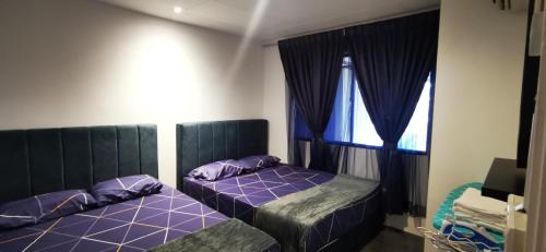 a bedroom with two beds with purple pillows and a window at Tanjung Tuan Beach Regency - Hermis Theme 1 Car Park in Kampong Baharu