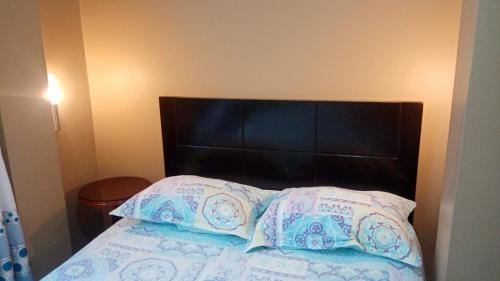 a bed with a black headboard and two pillows at Strenua - Las Quintanas in Trujillo