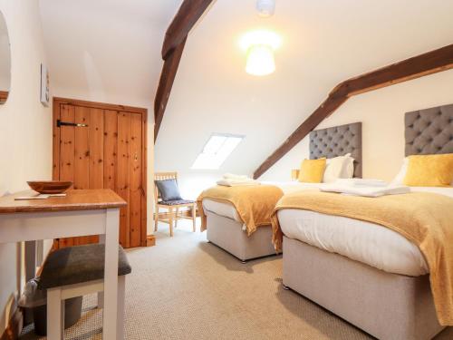 a bedroom with two beds and a desk and a table at The LinneyThe West Dry in St Austell