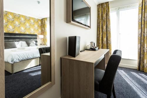 a hotel room with a bed and a desk with a television at The Residence Hotel at The Nottinghamshire Golf & Country Club in Nottingham