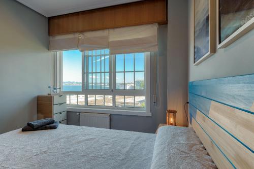 a bedroom with a bed and a large window at San Amaro Beach 3 by TheBlueWaveApartments com in A Coruña