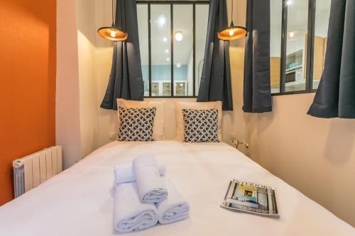 - une chambre avec un lit, des serviettes et un magazine dans l'établissement WS Marais - Musée Pompidou, à Paris