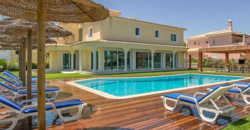 a house with a swimming pool with chairs and an umbrella at Dream Villa with Luxury Services - PROMOTION Last dates! in Vilamoura