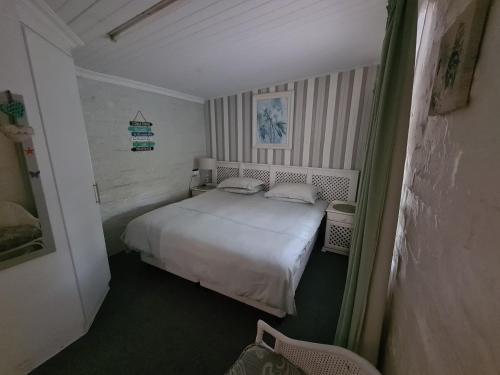 a small bedroom with a white bed and a chair at Knysna Self Catering Accommodation in Knysna