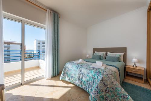a bedroom with a bed and a large window at Apartamento Monarquia - T3 Quarteira in Quarteira