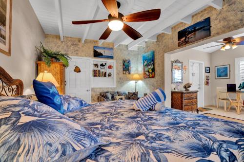 Island Bay Resort في كي لارغو: غرفة نوم بسرير ازرق وبيضاء مع مروحة سقف