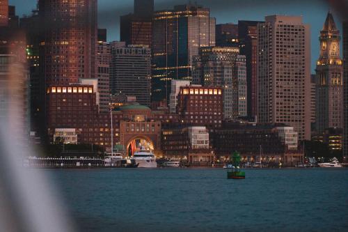 a city skyline at night with a boat in the water at Boston Harbor Hotel in Boston